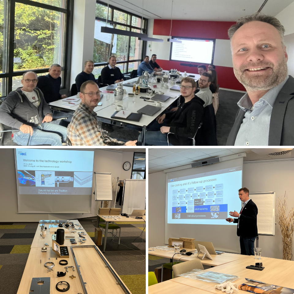 Gruppe von Menschen bei einem Workshop an einem großen Besprechungstisch, Präsentation mit technischen Inhalten und ausgestellte Werkstücke in Tagungsraum.