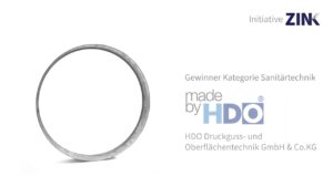 Metallring auf weißem Hintergrund mit Text zur Auszeichnung des Gewinners in der Kategorie Sanitärtechnik von HDO Druckguss- und Oberflächentechnik GmbH & Co. KG, Initiative ZINK-Logo oben rechts